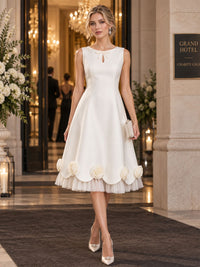 Front view of a satin A-line mother of the bride dress with jewel neckline, keyhole detail and 3D floral tea-length hem.