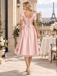 Back view of a satin A-line mother of the bride dress with lace-up corset back, tea-length skirt and 3D rose appliqués.